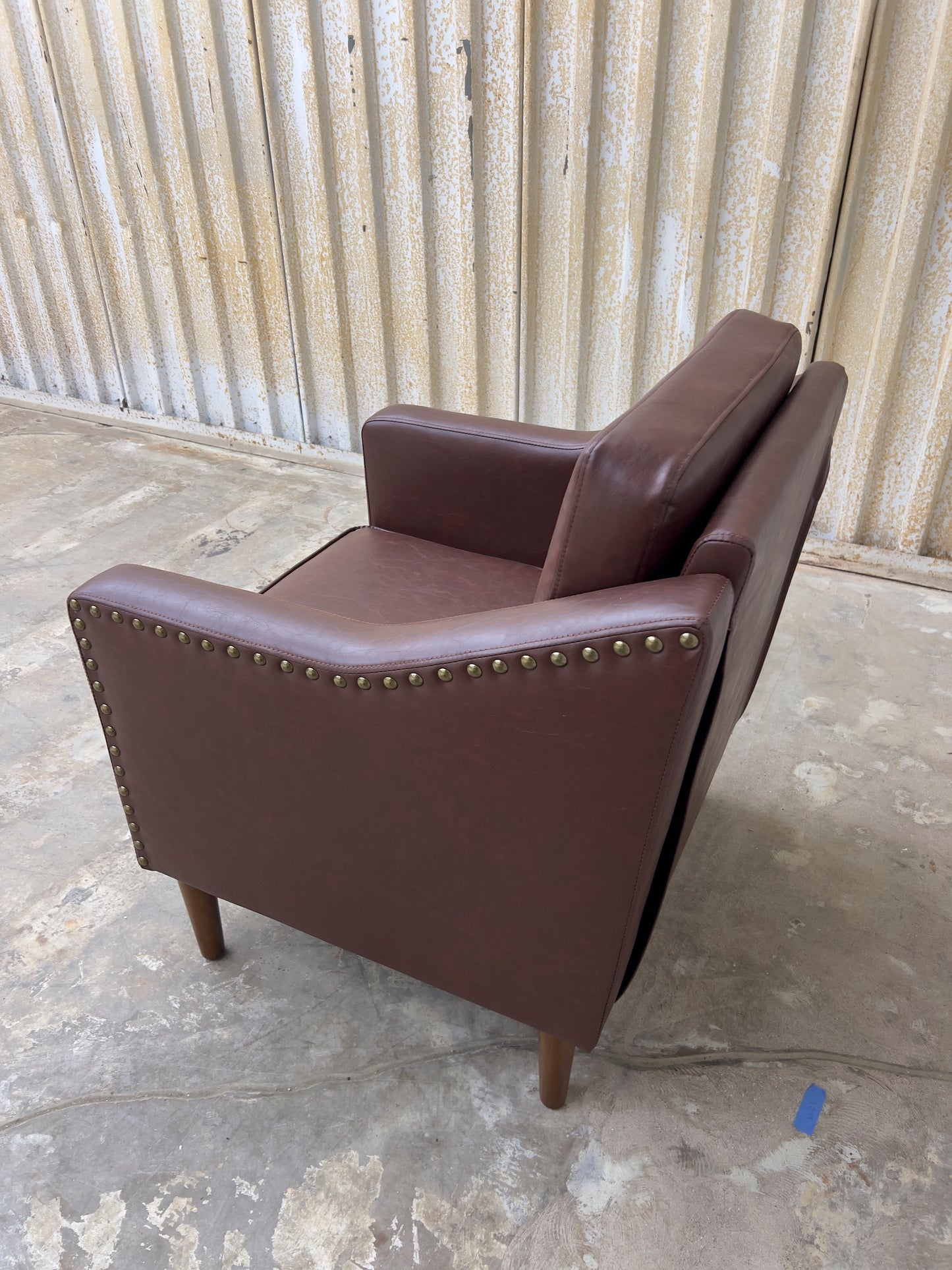 Vegan Leather Brown Armchair featuring solid wood legs and nailhead trim.