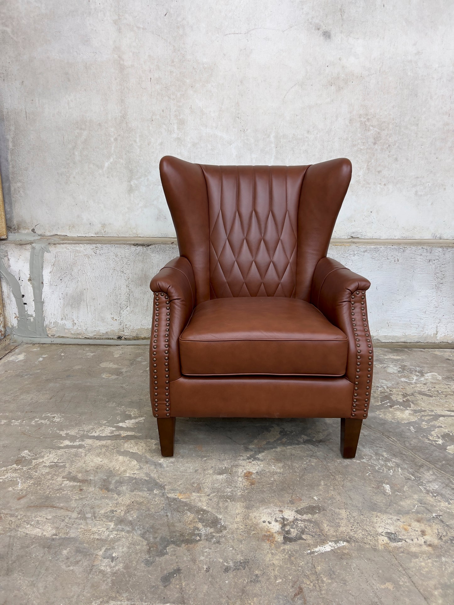 Genuine leather armchair featuring nailhead trims and solid wood legs.