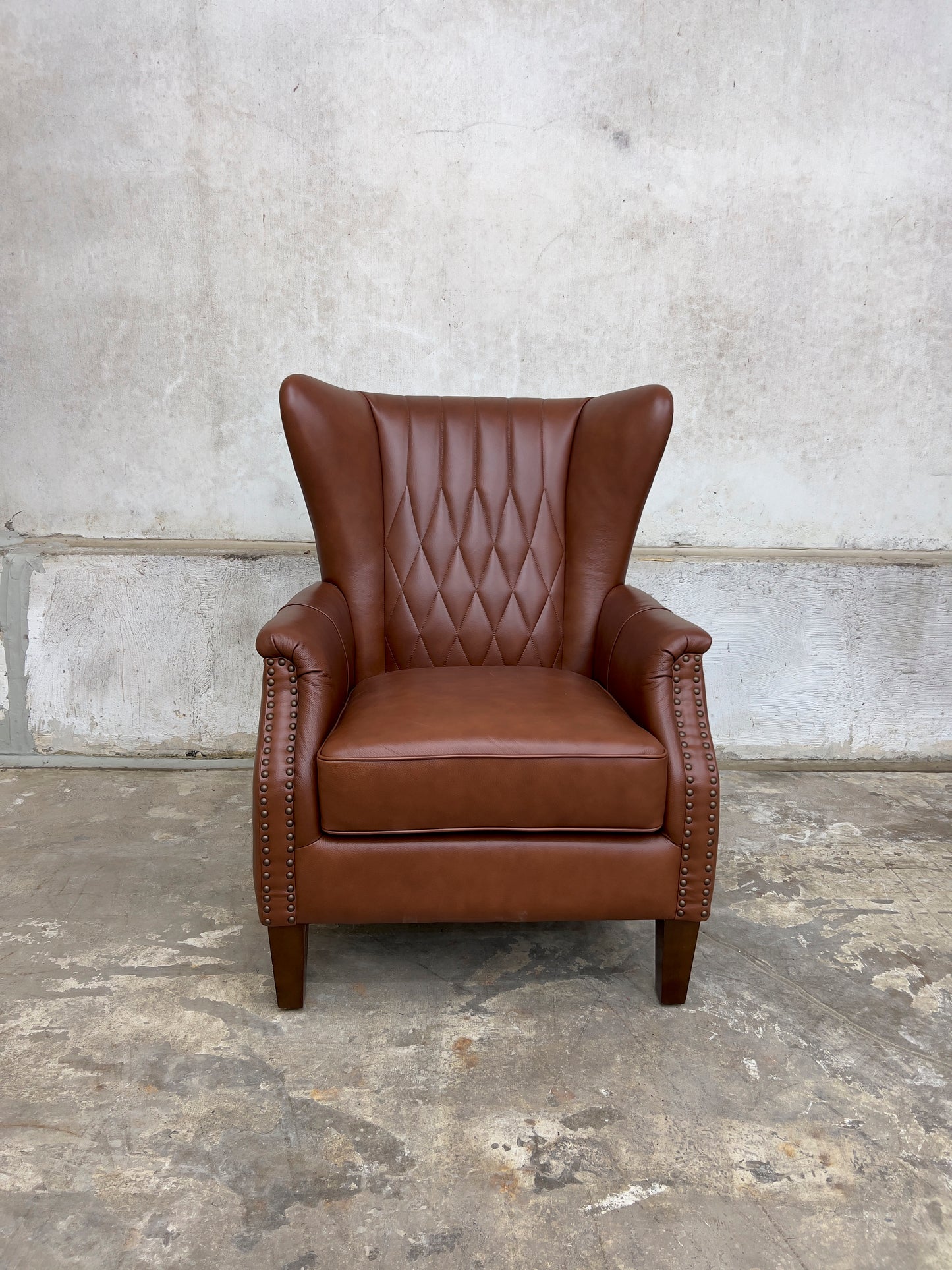 Genuine leather armchair featuring nailhead trims and solid wood legs.