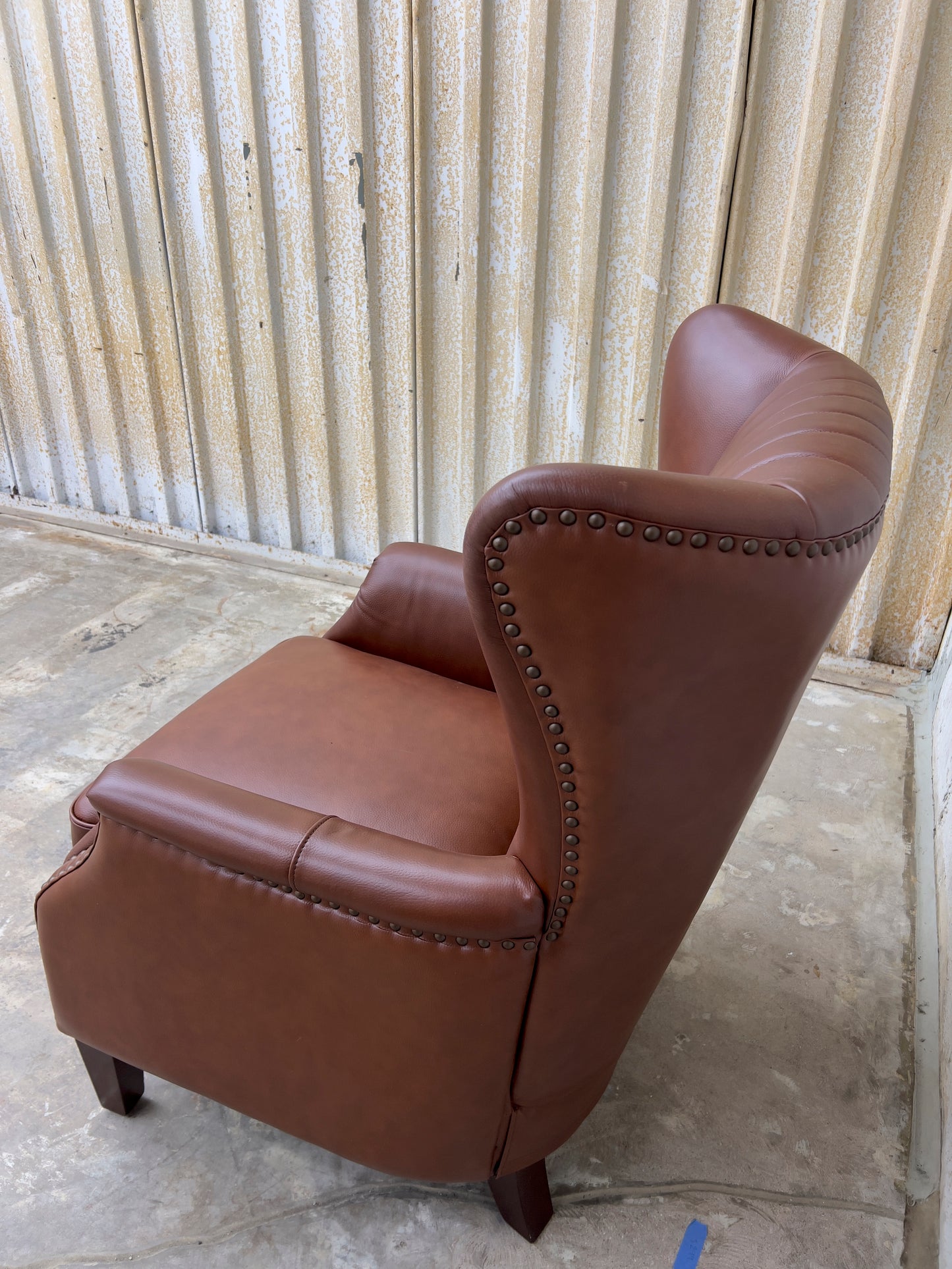 Genuine leather armchair featuring nailhead trims and solid wood legs.