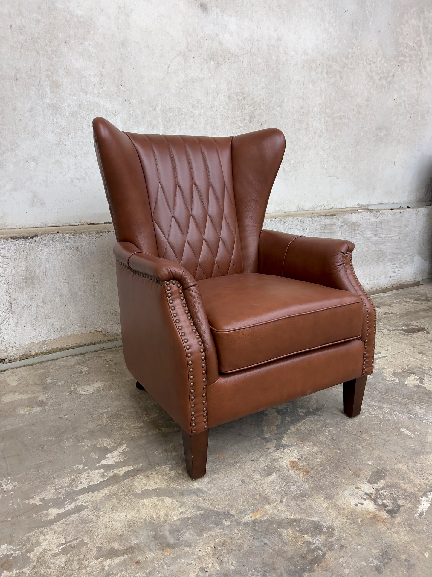 Genuine leather armchair featuring nailhead trims and solid wood legs.