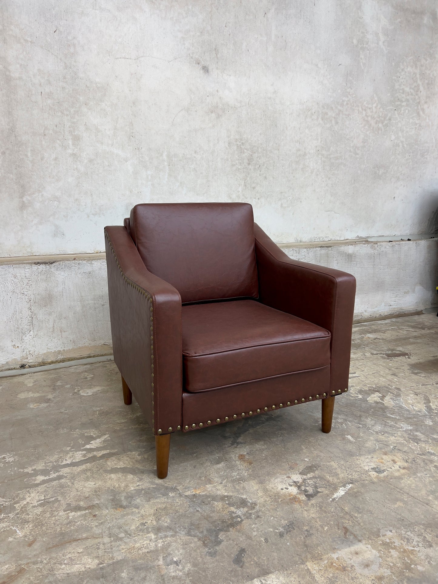 Vegan Leather Brown Armchair featuring solid wood legs and nailhead trim.