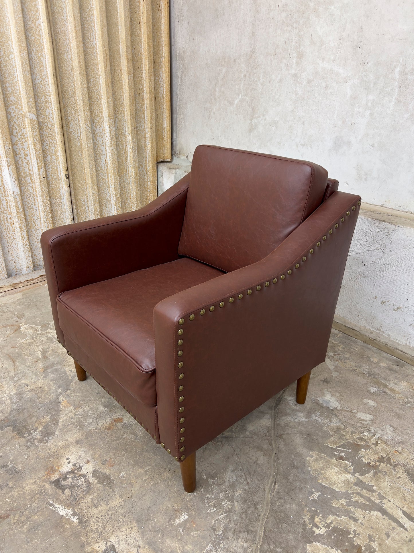 Vegan Leather Brown Armchair featuring solid wood legs and nailhead trim.