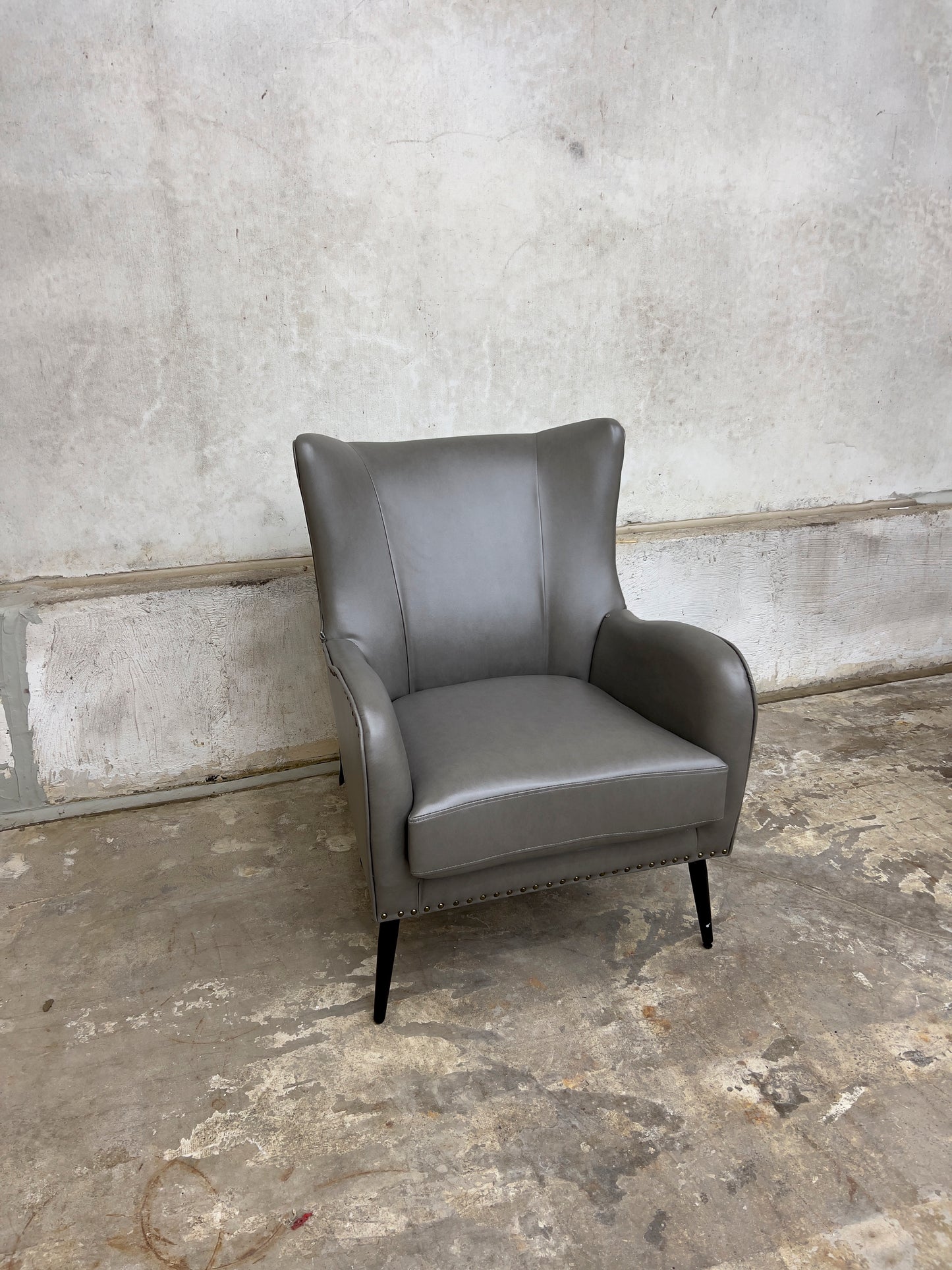 Grey Armchair, which features vegan leather upholstery, nailhead trim, and metal legs.
