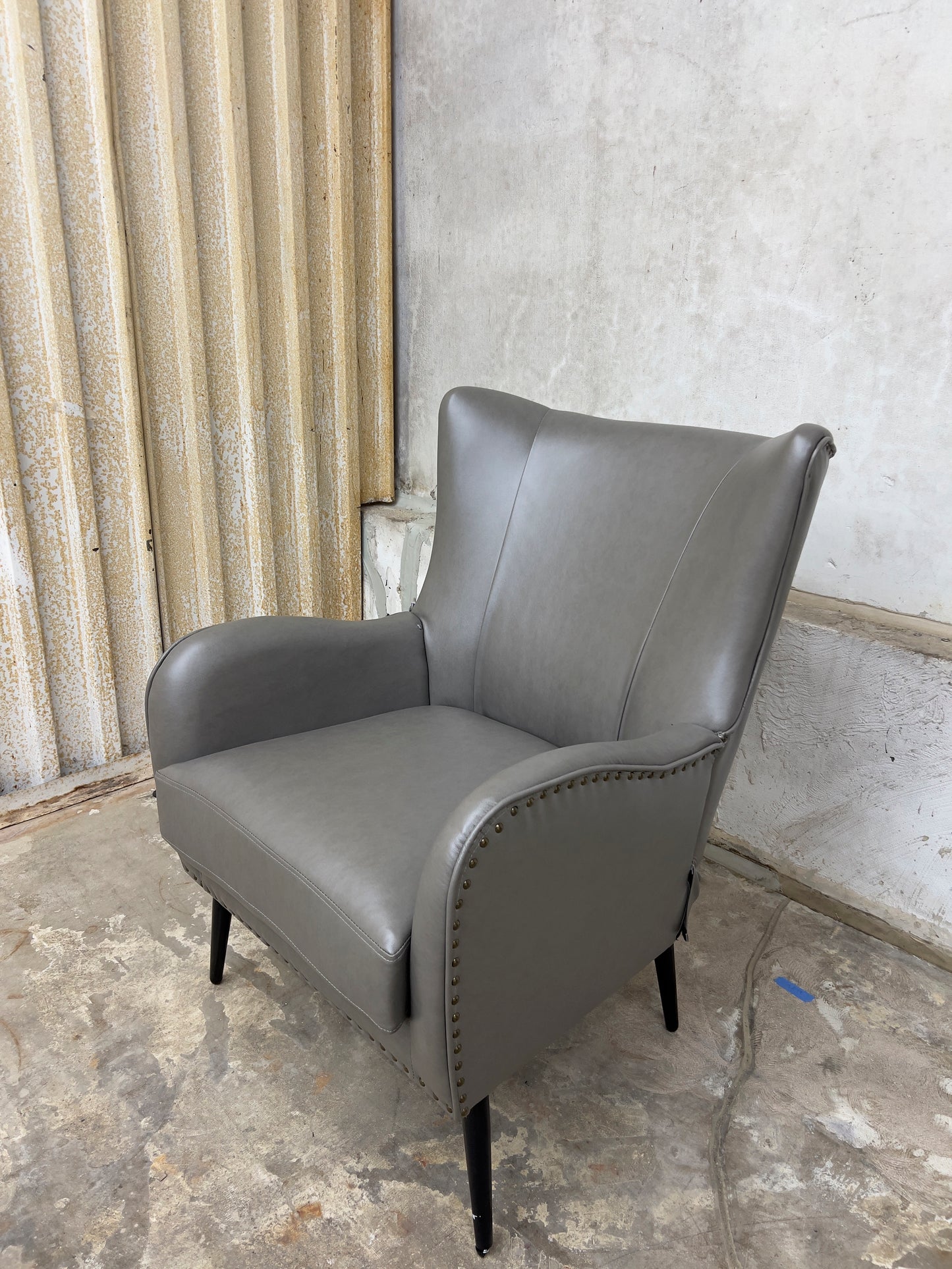 Grey Armchair, which features vegan leather upholstery, nailhead trim, and metal legs.