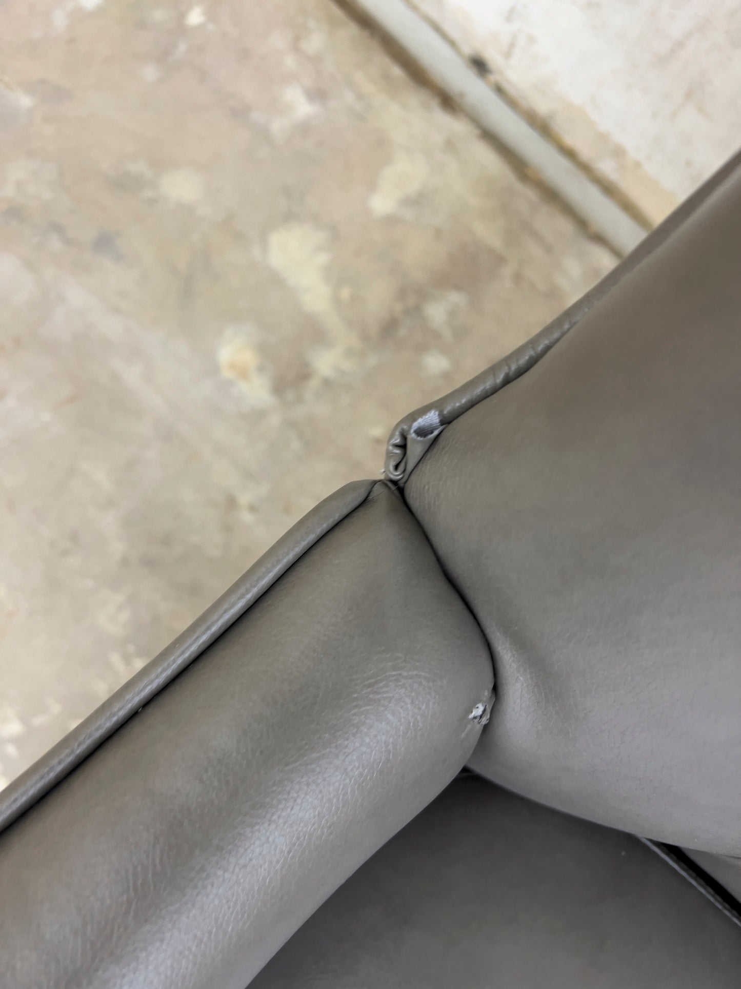 Grey Armchair, which features vegan leather upholstery, nailhead trim, and metal legs.