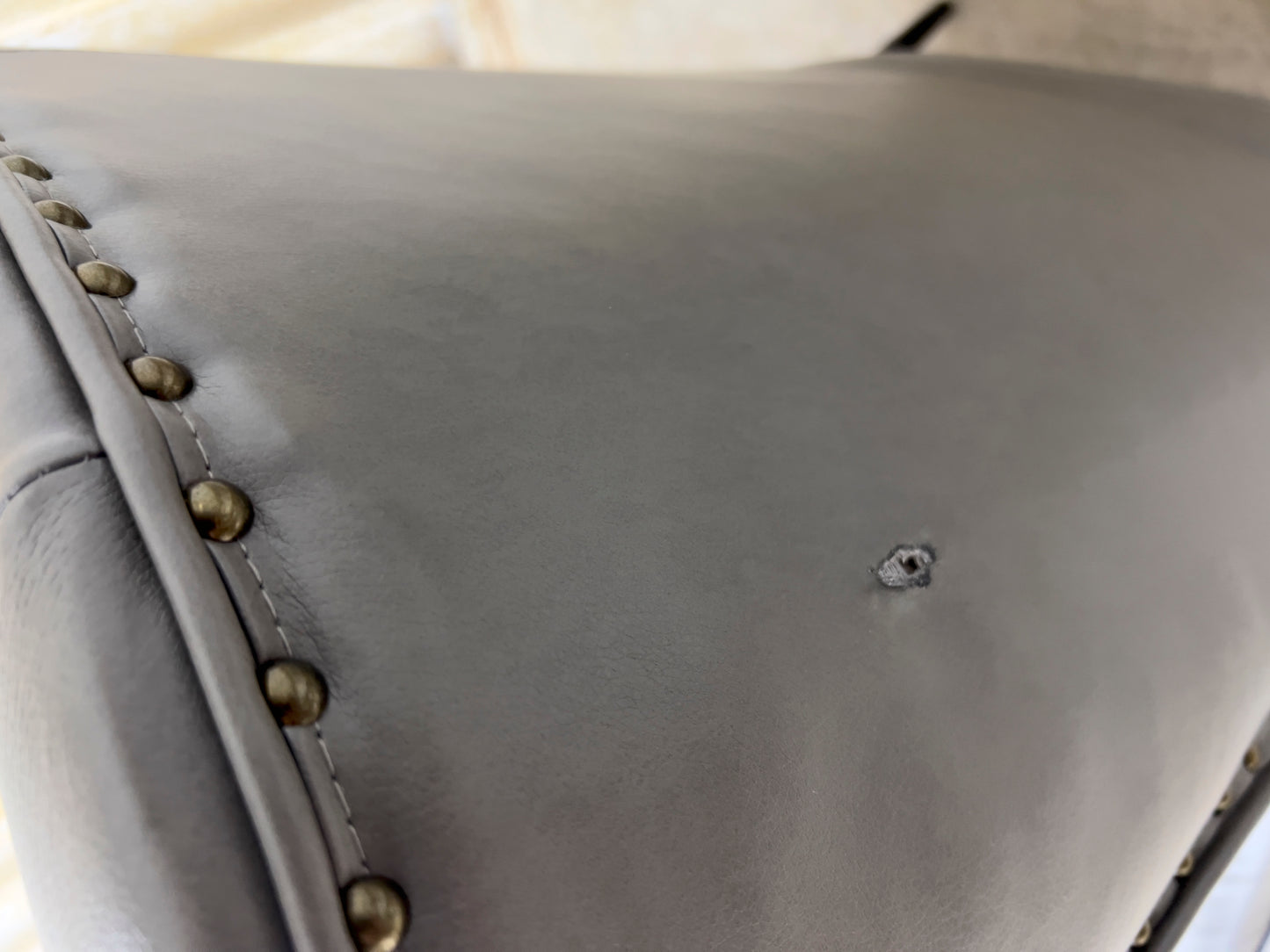 Grey Armchair, which features vegan leather upholstery, nailhead trim, and metal legs.