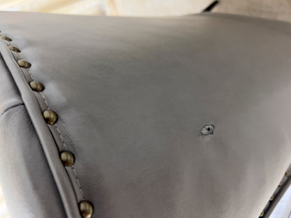 Grey Armchair, which features vegan leather upholstery, nailhead trim, and metal legs.